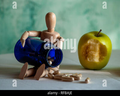 Une figurine en bois avec un piqué et un conteneur bleu apple avec la fibre végétale comprimés sur une table Banque D'Images