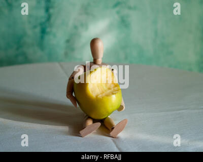 Une figurine en bois avec un mordu de green apple sur une table Banque D'Images