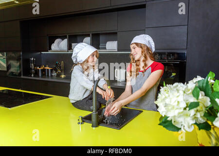 Deux filles avec le chef hat serrant et s'amuser en cuisine. Soeurs petit enfant et adolescente la cuisson des aliments sains à la maison. Enfance, famille, househ Banque D'Images