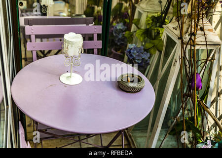 Cigarette dans le cendrier sur la table ronde, entre décoration avec des fleurs en plastique et de vraies plantes en italien terrasse dans un jour d'hiver Banque D'Images