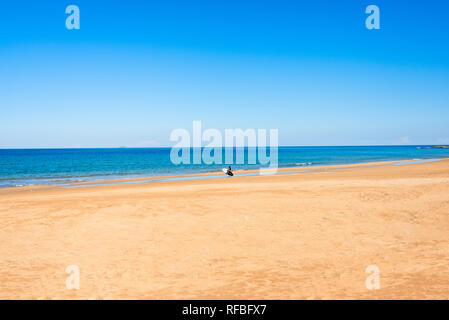 Homme méconnaissable avec paddle board sur la plage de sable fin de matin d'été. Mer Méditerranée Arina sand beach water sports paradis. Les vacances d'été Banque D'Images