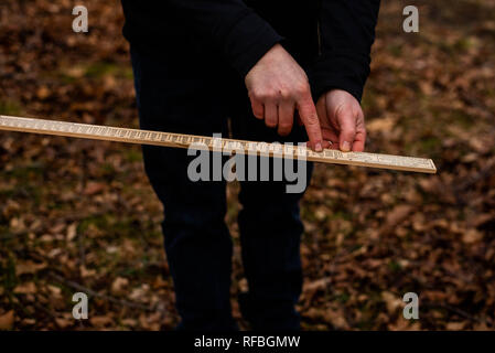 Trois ans girl picking up sticks dans une cour sur une chaude journée d'été. Banque D'Images