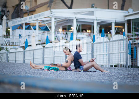 Couple assis dos à dos sur la plage à Amalfi en Italie. Banque D'Images