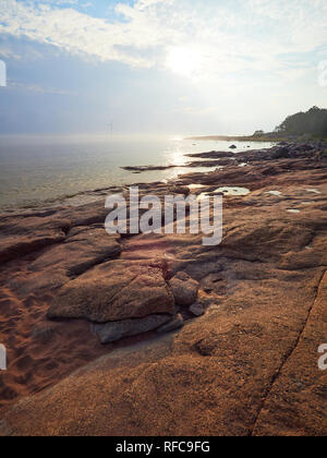 Soirée d'été ensoleillé par la mer. Moulins à vent lointain sur l'arrière-plan. Des rochers et du sable sur la plage. Reposaari, Pori, Finlande. Prise de vue au grand angle. Banque D'Images