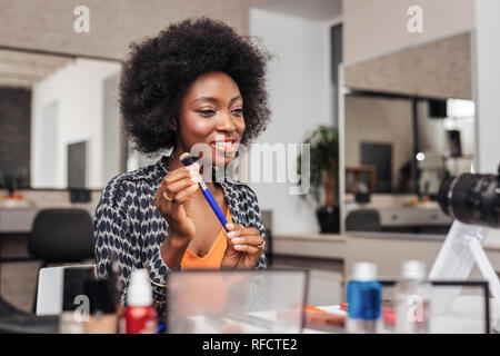 Belle femme africaine avec le rouge à lèvres brillant à amusé Banque D'Images