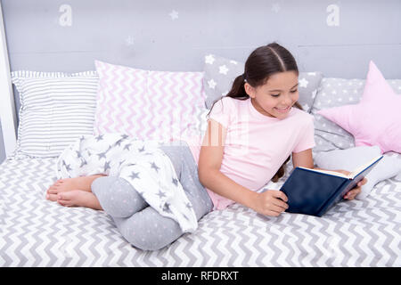 Histoire fascinante. Petite fille lay lit avec oreillers lire livre. Kid se préparer à aller au lit. Temps pour soir histoire fascinante. Kid fille cheveux longs pyjamas mignons vous détendre et lire la fascinante histoire d'adresses. Banque D'Images