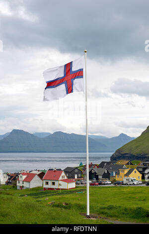 Le drapeau des Îles Féroé au-dessus mais confortables et disposent village situé sur la pointe nord-est de l'île de Eysturoy, dans les Îles Féroé Banque D'Images