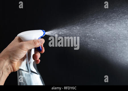 La main de détergent de pulvérisation avec vaporisateur sur fond noir Banque D'Images
