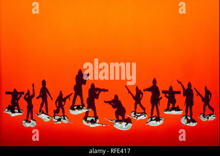 Groupe des petits soldats armés avec ombres combattre l'un contre l'autre le fond coucher de soleil orange rouge Banque D'Images