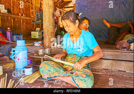 CHAUNG THA, LE MYANMAR - 1 mars, 2018 : femme birmane rend les bandes étroites de bambou pour le tissage des choses différentes - chapeaux coniques, plateaux, paniers, w Banque D'Images