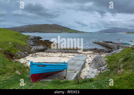 Bateau bleu et rouge à la jetée près de Huisinis, Isle of Harris, de l'Écosse. La recherche à travers l'eau vers l'escarpement. Banque D'Images