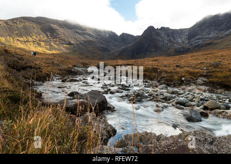 Deux randonneurs à une rivière de la Fée piscines sur Ile de Skye avec de grandes montagnes pendant l'automne (Ile de Skye, Ecosse, Royaume-Uni, Europe) Banque D'Images