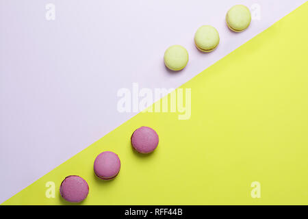 Fond jaune et rose avec deux rangées de macarons Banque D'Images