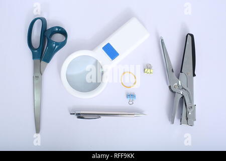 Photo de l'agrafeuse, stylo à billes, scissor, trombone et loupe. Isolé sur le fond blanc. Banque D'Images