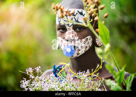 KIBISH, ÉTHIOPIE - 22 août 2018 : une femme non identifiée de Surmi tribu, avec visage peint et décors naturels des congés et des fleurs dans une couronne. Banque D'Images