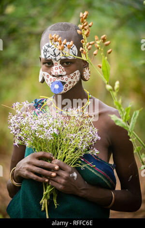 KIBISH, ÉTHIOPIE - 22 août 2018 : une femme non identifiée de Surmi tribu, avec visage peint et décors naturels des congés et des fleurs dans une couronne. Banque D'Images