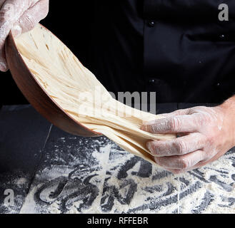 Les mains de l'homme blanc pétrir la pâte de farine de blé noir sur fond de bois Banque D'Images