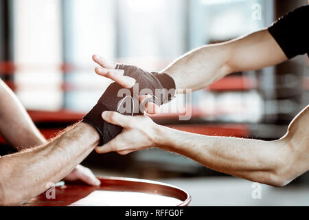 Close-up of a entre les mains des hommes enveloppés de bandages de boxe dans la salle de sport Banque D'Images