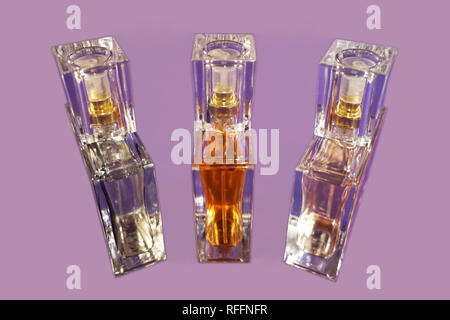 Parfum dans trois petites bouteilles en verre sur le fond de couleur lilas Banque D'Images