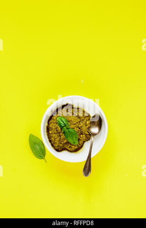 Sauce au pesto de basilic frais sur fond jaune mise à plat. Banque D'Images