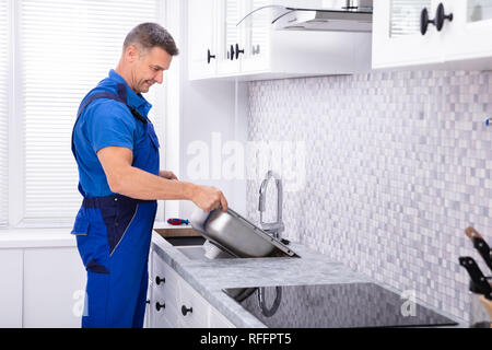 Photo de mâle mature Workman fixant un évier de cuisine Banque D'Images