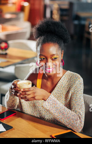 Femme afro-américaine avec un miroir lumineux de boire du café Banque D'Images