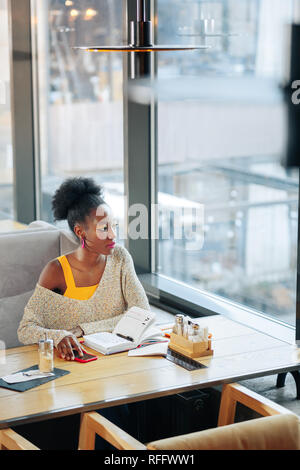 Femme afro-américaine frisé assis près de la fenêtre Banque D'Images