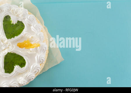 Gâteau crème blanc avec cœurs verts sur fond bleu en plongée des Banque D'Images