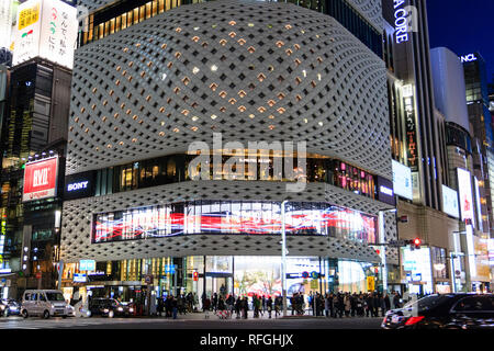 De près de l'édifice Place Ginza blanc avec façade en aluminium bleu pendant l'heure. Allumé. Premier plan, rue avec le trafic passé. Banque D'Images