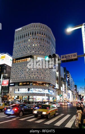 Le livre blanc Place Ginza building et sa façade en aluminium. La nuit, traversée de la rue en premier plan avec 4 Ginza signer et arrêter la lumière. Le trafic. Banque D'Images