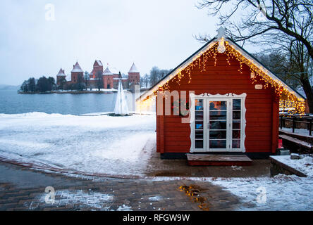 Lac gelé, neige et petite maison en bois avec éclairage sur un lac à Trakai, Vilnius, Lituanie Banque D'Images