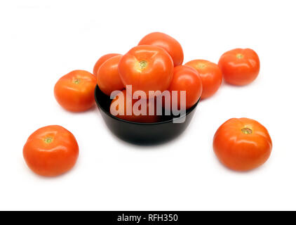 De nombreux fruits rouges tomates appétissantes en noir cuvette ronde et dispersés sur fond blanc gros plan vue avant Banque D'Images