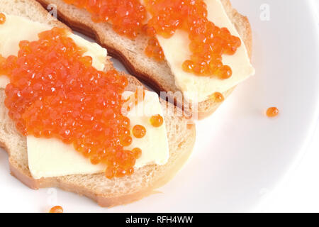 Deux sandwiches avec du beurre et du caviar de saumon sur pain blanc se trouve sur une plaque ronde, isolé sur fond blanc Vue de dessus Banque D'Images