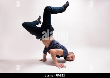 Danseur élégant faisant figures de breakdance. Debout sur les deux mains, la tête en bas et les deux jambes. Studio isolé shot against white background Banque D'Images