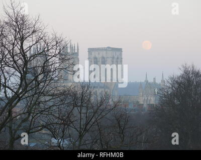 La fin de l'après-midi en janvier 2019 et une supermoon brille dans le ciel plus d'un ciel voilé la cathédrale de York dans la distance. Banque D'Images