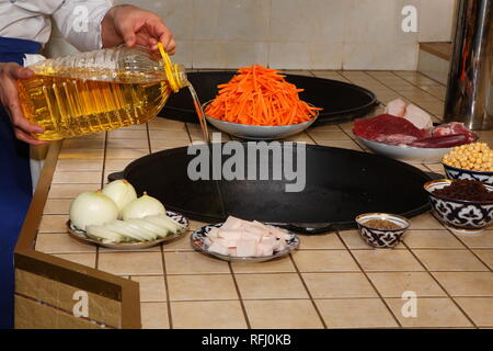 Pilau de cuisson dans la cuisine d'un restaurant oriental. Verse l'huile dans le chaudron Banque D'Images