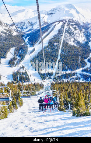 Les skieurs non identifiables sur télésiège remontant une pente de ski dans la montagne enneigée (éventail des Rocheuses canadiennes. Banque D'Images
