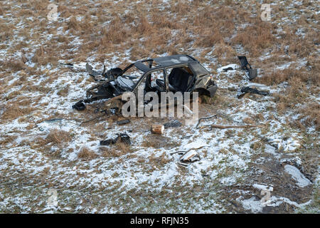 L'épave d'une voiture dévasté sur un pré. Voiture démonté squelette. Saison Hiver. Banque D'Images