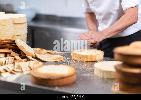 Chef pâtissier de couper le gâteau éponge sur couches. Processus de la production de gâteaux . Banque D'Images