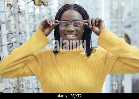 Jeune femme africaine le choix de montures de lunettes de prescription dans la boutique de l'opticien. Banque D'Images