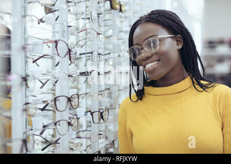 Jeune femme africaine le choix de montures de lunettes de prescription dans la boutique de l'opticien. Banque D'Images