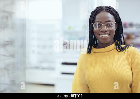 Jeune femme africaine le choix de montures de lunettes de prescription dans la boutique de l'opticien. Banque D'Images