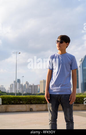 Young Asian Woman wearing sunglasses tout en vous relaxant à la Banque D'Images