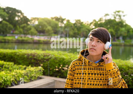 Young Asian Woman wearing headphones tout en vous relaxant à la Banque D'Images