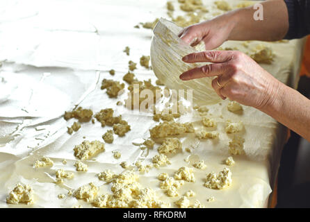 La pâte à strudel, étiré sur une table de cuisine et de l'ajout du fromage sur elle Banque D'Images