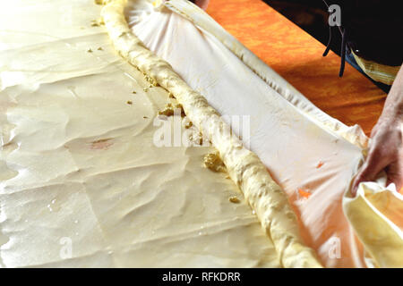 La pâte de roulement pour strudel aux pommes avec du fromage sur une table de cuisine Banque D'Images