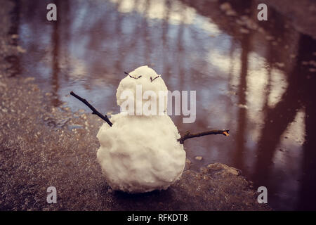 Bonhomme de printemps. bonhomme de neige dans le ressort de la neige sale sur l'arrière-plan de flaques d'eau sale bonhomme. Banque D'Images