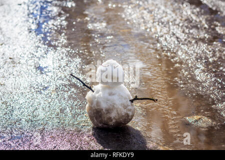 Bonhomme de printemps. bonhomme de neige dans le ressort de la neige sale sur l'arrière-plan de flaques d'eau sale bonhomme. Banque D'Images