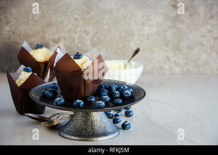 Délicieux frosting cupcakes décorés avec du fromage à la crème et de bleuets frais Banque D'Images
