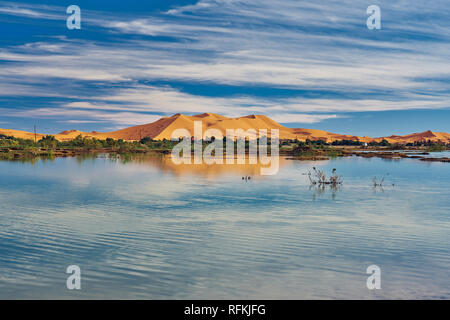 Une colline de sable (dune) d'Erg Chebbi et réflexion sur le lac. Paysage prise près de la ville de Merzouga, Sahara, Maroc en novembre. Banque D'Images